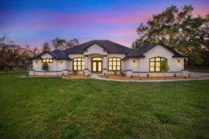 The Wyrick is a single-story white stucco 3 bedroom home with arched windows and a central entryway under a sunset sky. Townsley Construction in Florida