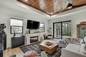 Living room in The Harper with a fireplace, television, area rug, square coffee table, and sliding glass doors leading to a backyard. Townsley Construction in Florida