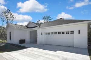 A single-story, three-bedroom Harper house with a white exterior, a two-car garage, and the address number 2396 displayed on the front wall. Townsley Construction in Florida