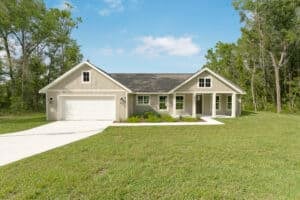 Single-story suburban 3 bedroom house with beige vertical siding, a two-car garage, and a covered front porch. Townsley Construction in Florida