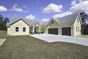 Single-story Purvis house with a beige stucco exterior, stone accents, a gray shingle roof, and a three-car garage. Townsley Construction in Florida