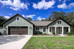 A single-story, 3 bedroom green house with a two-car garage, white trim, and a front porch. Townsley Construction in Florida